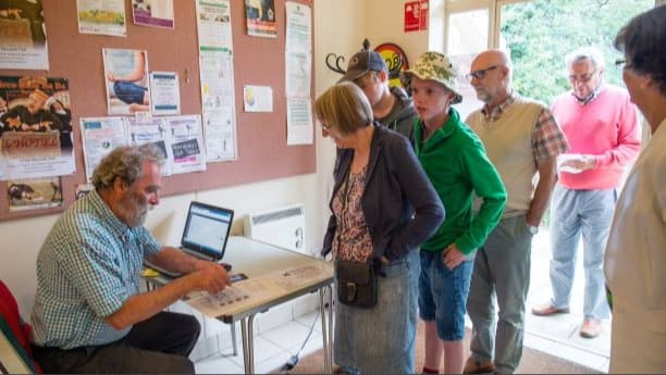Image: Man selling tickets with queue of people Photo Credit : Keith Morris 